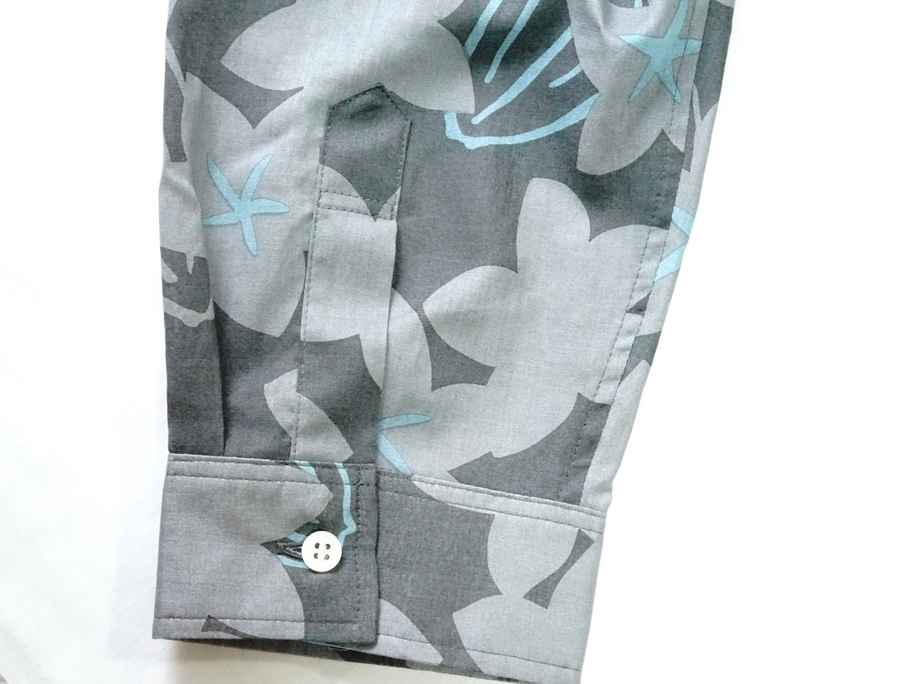 AMONGの花柄シャツ スターフルーツ シルエット 木柄。チャコールにターコイズが映えるスターフルーツの星が印象的。コットン100%が日常に心地よい一枚。